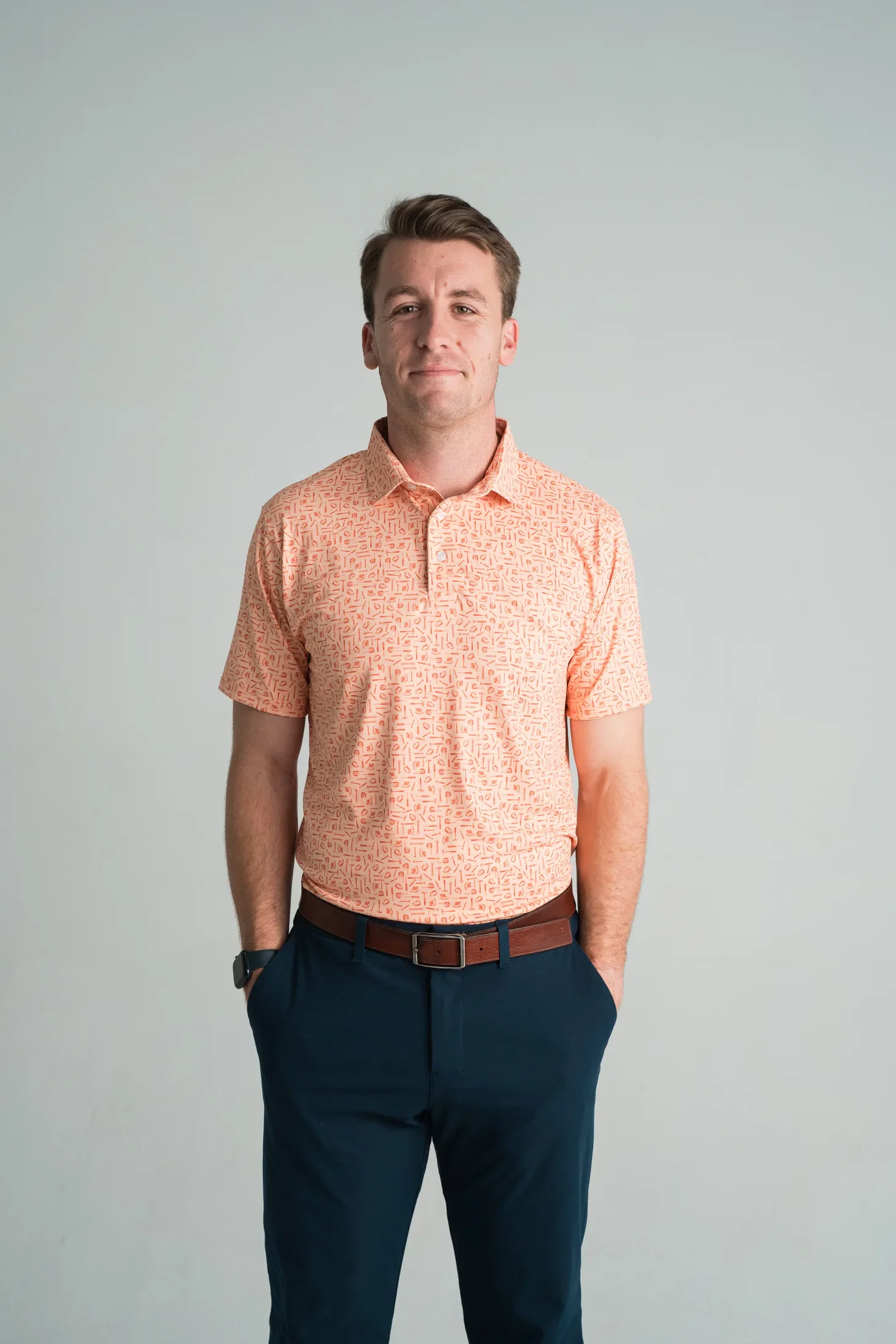 Model wearing a coral polo with a custom tool pattern