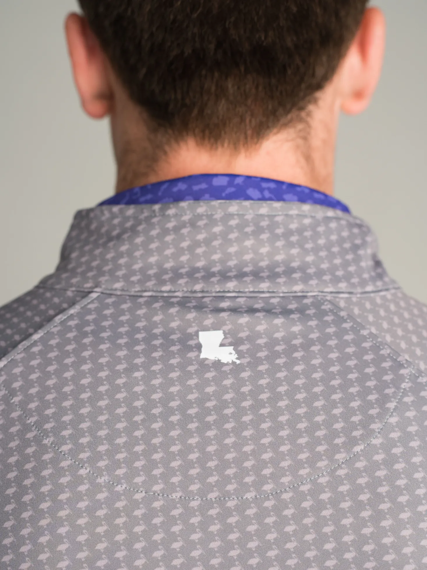 Back of a gray pelican print quarter zip with a white Louisiana heat transfer below the collar