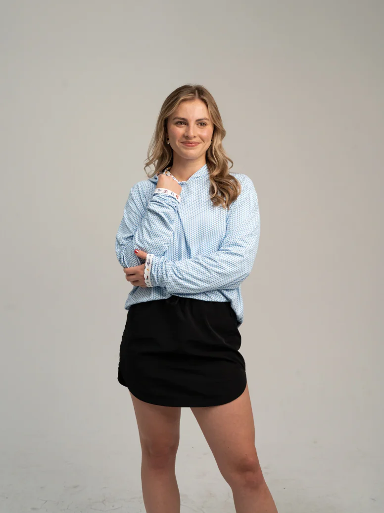 Woman wearing a light blue micro print hooded long sleeve and a black skirt