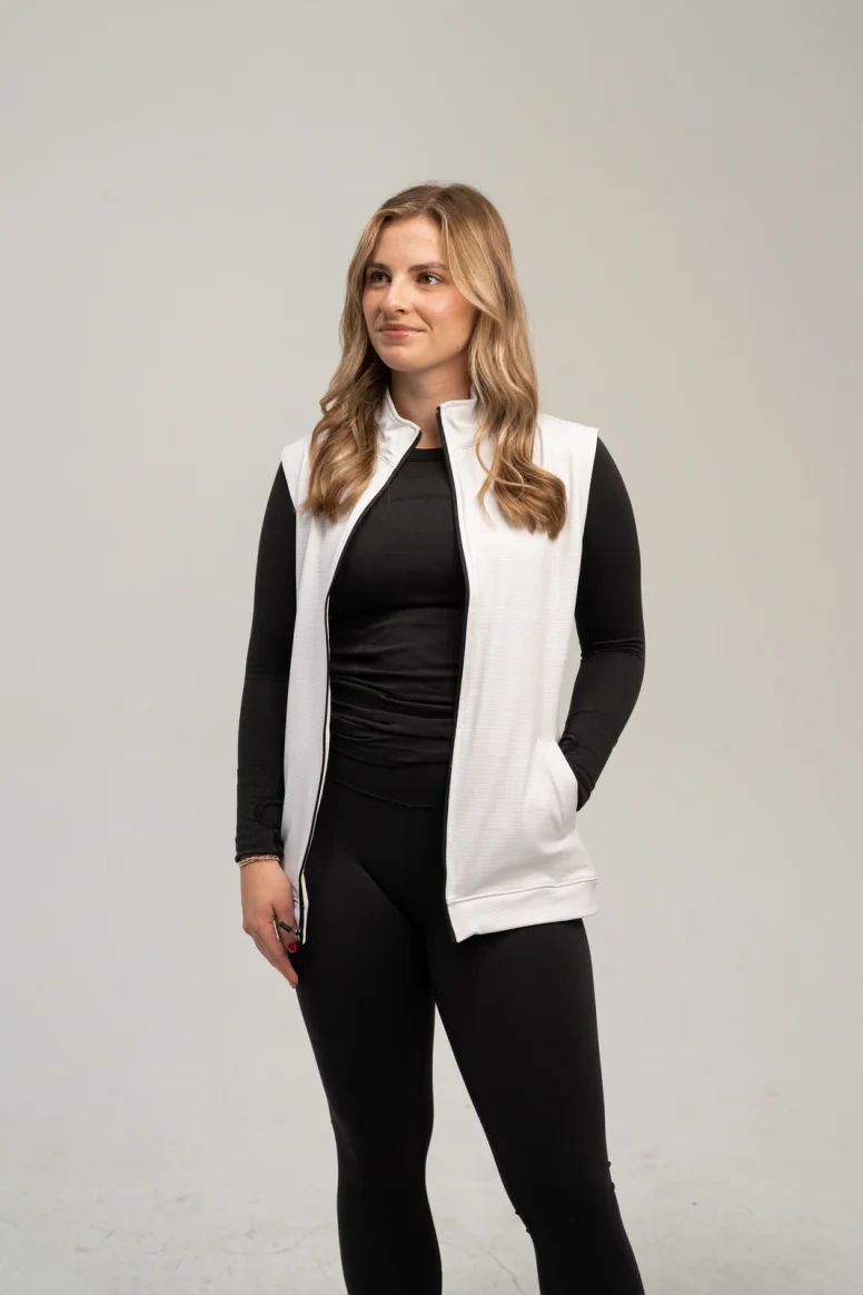 Woman wearing an open white full zip vest over a black top