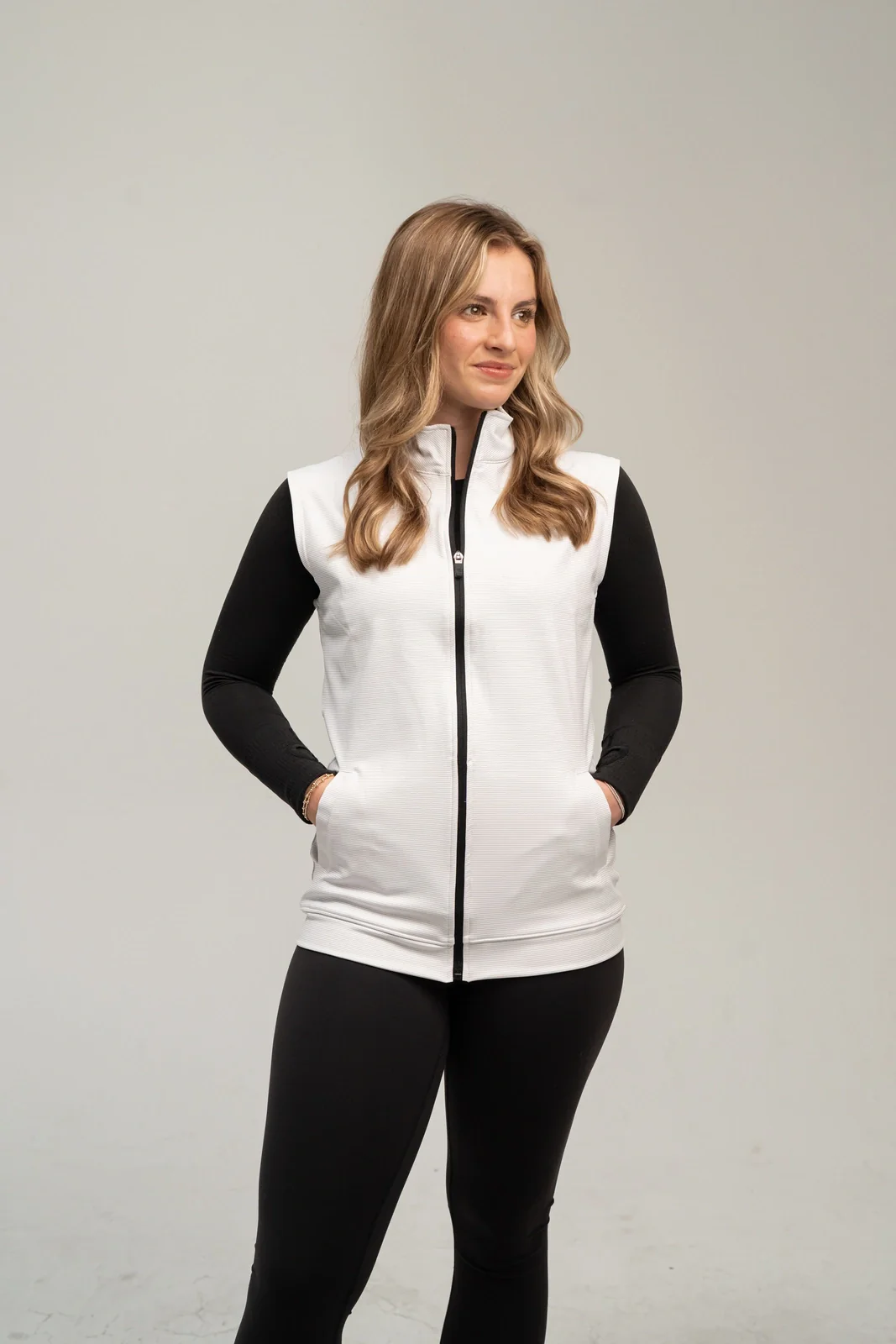 Woman wearing a white full zip vest over a black long sleeve top