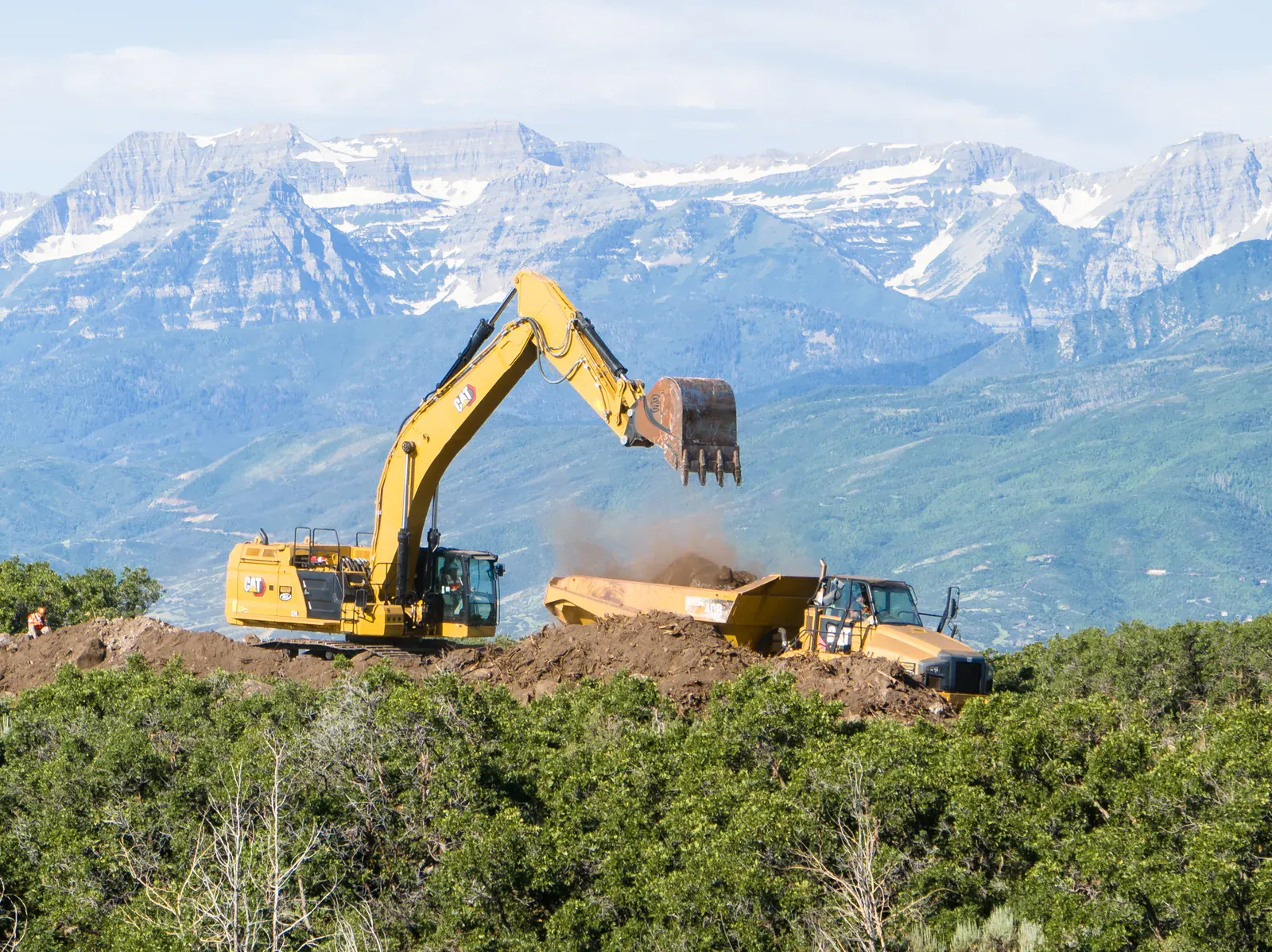 Excavator loading an earthmover on a mountain jobsite