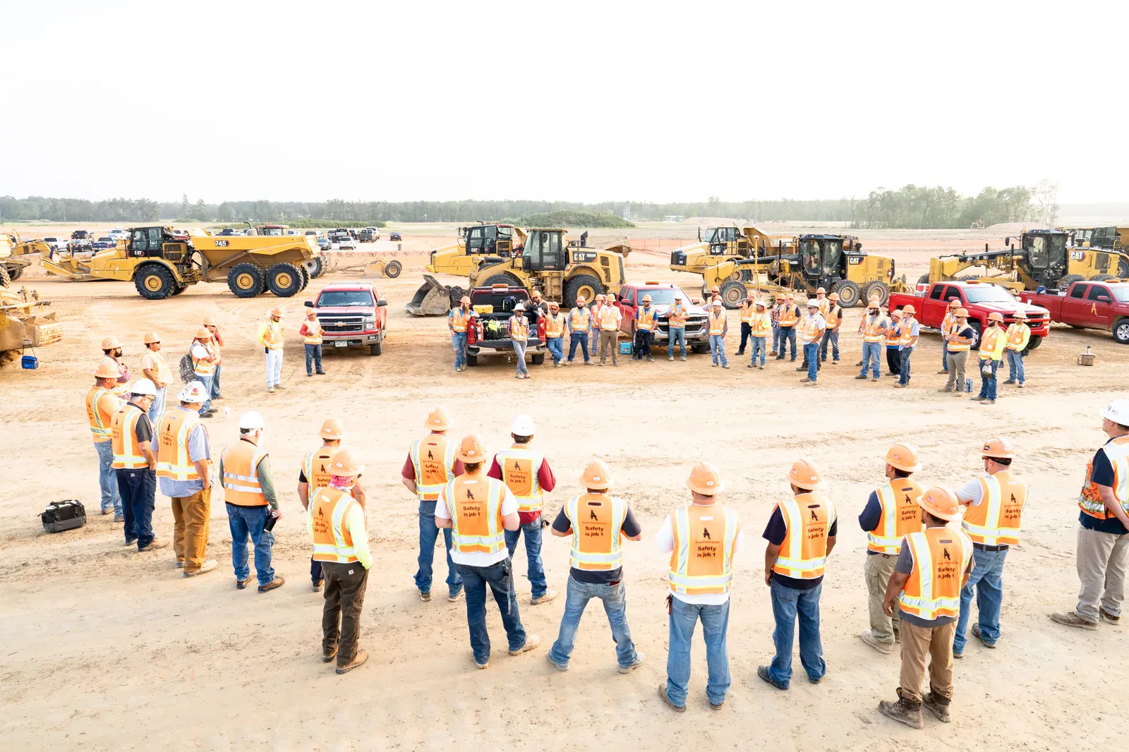 Construction crew gathered at a jobsite with earthmoving equipment