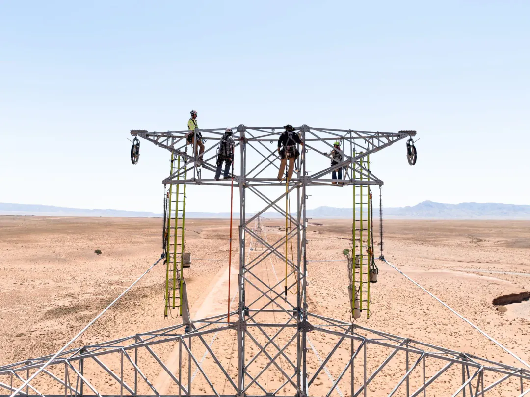 Workers on a metal structure in a desert landscape