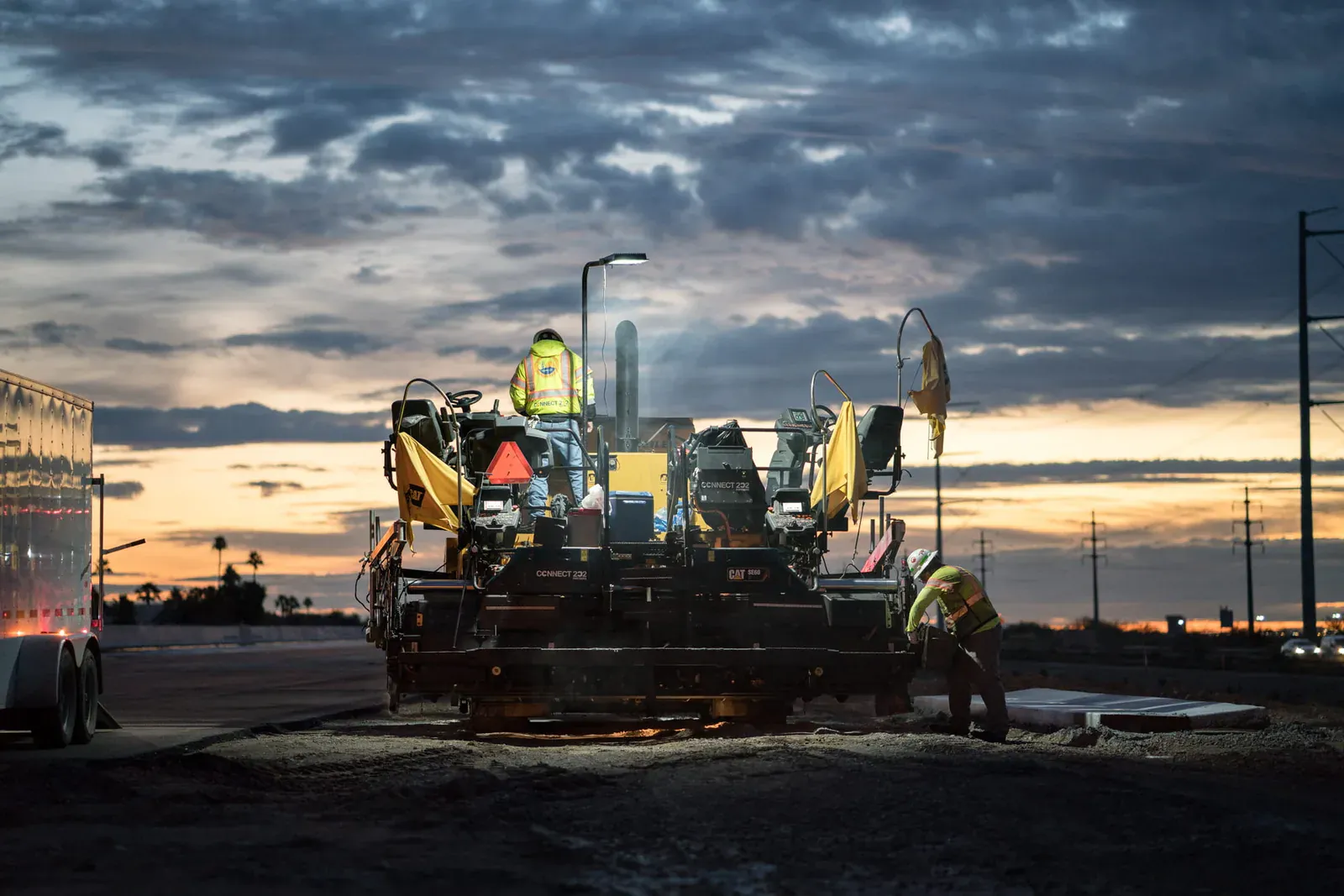Road construction crew working at sunset