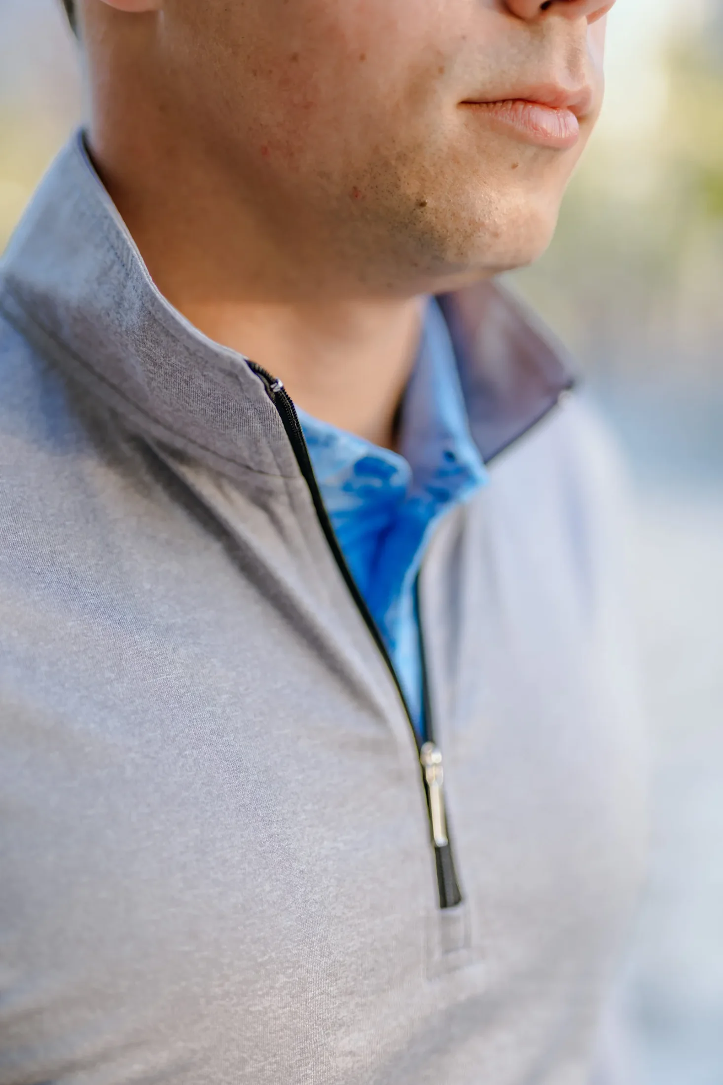 Close view of a custom quarter zip collar, zipper, and patterned polo fabric