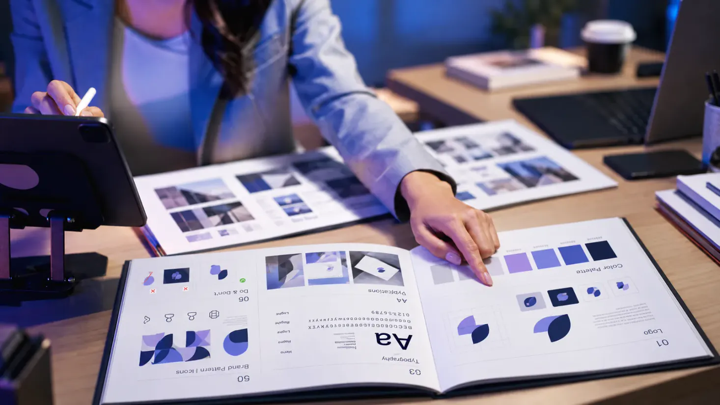 Designer reviewing a printed brand guidelines packet with logo, color palette, and typography pages